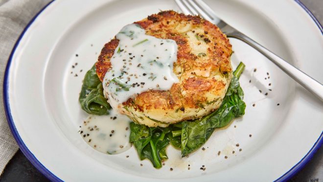 Smoked Salmon Hash Browns with Parsley Sauce served on a bed of spinach in a white dish