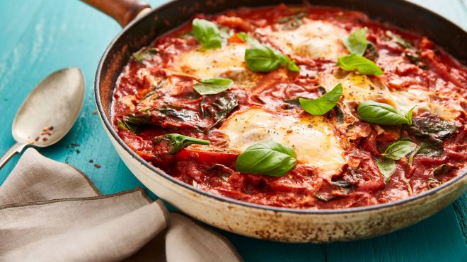 Smoky Baked Eggs served in a pan sprinkled with spinach