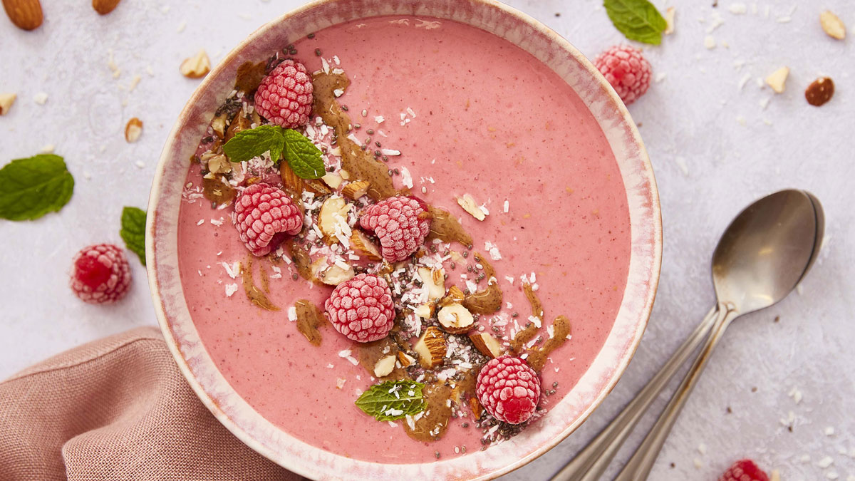 Frozen Smoothie Bowl served in a pink bowl, topped with frozen raspberries