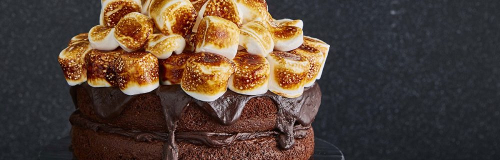 Smores Chocolate Cake served ona black cake dish, with toasted marshmallows on top