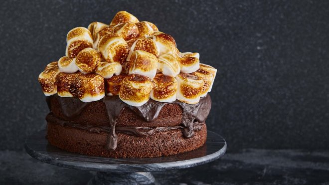 Smores Chocolate Cake served ona black cake dish, with toasted marshmallows on top