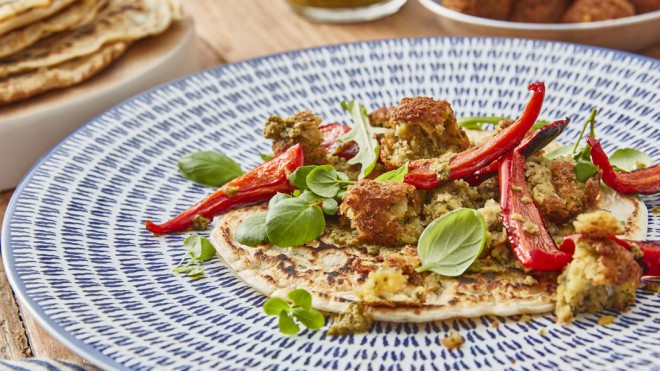 Spelt Pancakes with Falafels on a blue and white plate, topped with roasted red peppers and basil