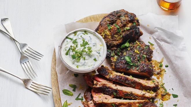Spiced Butterflied Leg of Lamb sliced and served on a wooden board with greek yoghurt mixed with mint and parsley