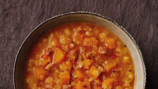 Spiced Red Lentil and Bacon Soup served in a white bowl topped with cracked black pepper