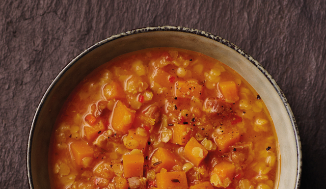 Spiced Red Lentil and Bacon Soup served in a white bowl topped with cracked black pepper