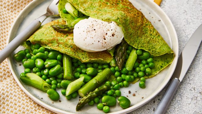 Spinach Blender Crepes served on a white plate, with spring greens and a poached egg