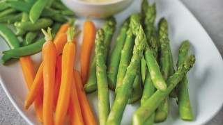 Simple Steamed Asparagus served on a white plate next to steamed carrots