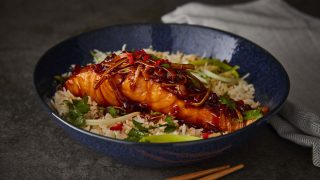 Sticky Vietnamese Style Salmon served in a blue bowl next to striped tablecloth
