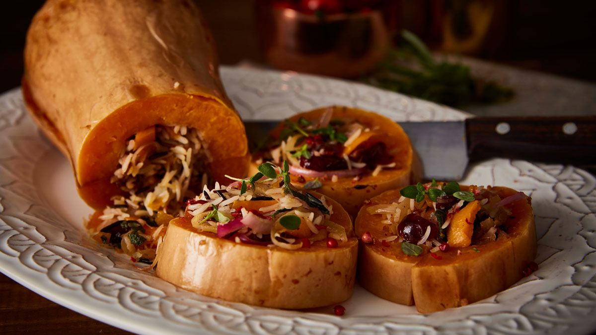 Roasted and Stuffed Butternut Squash (Vegan) served on a white plate and sliced to see the filling