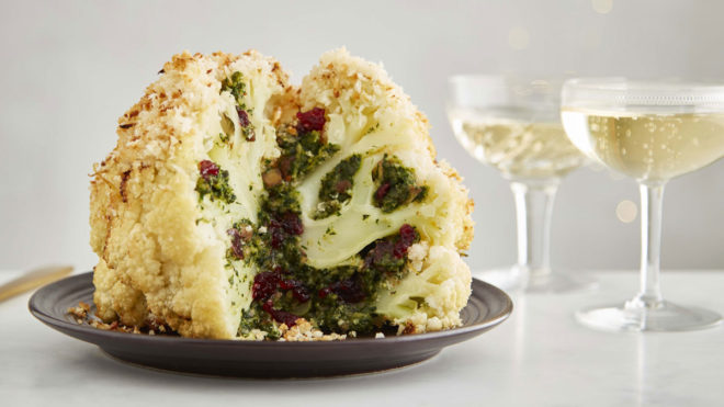 Whole Roasted Caulifower with Festive Stuffing served on a black plate