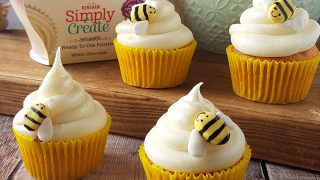 Honey White Chocolate Cupcakes served on a wooden board with decorative bees