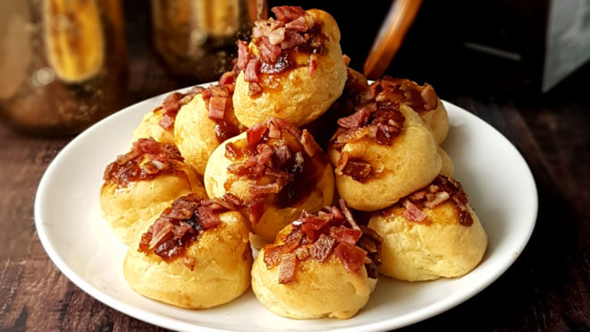 Bacon and Goats Cheese Profiteroles served on a white plate, piled on top of each other