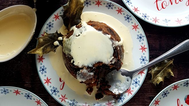 Traditional Christmas Pudding Served in a festive bowl drizzled with cream