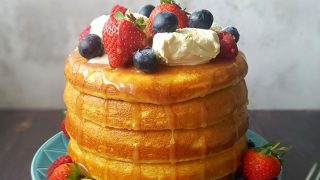 Fluffed Up Japanses Pancakes stocked on top of one another, topped with ice cream, berries and syrup