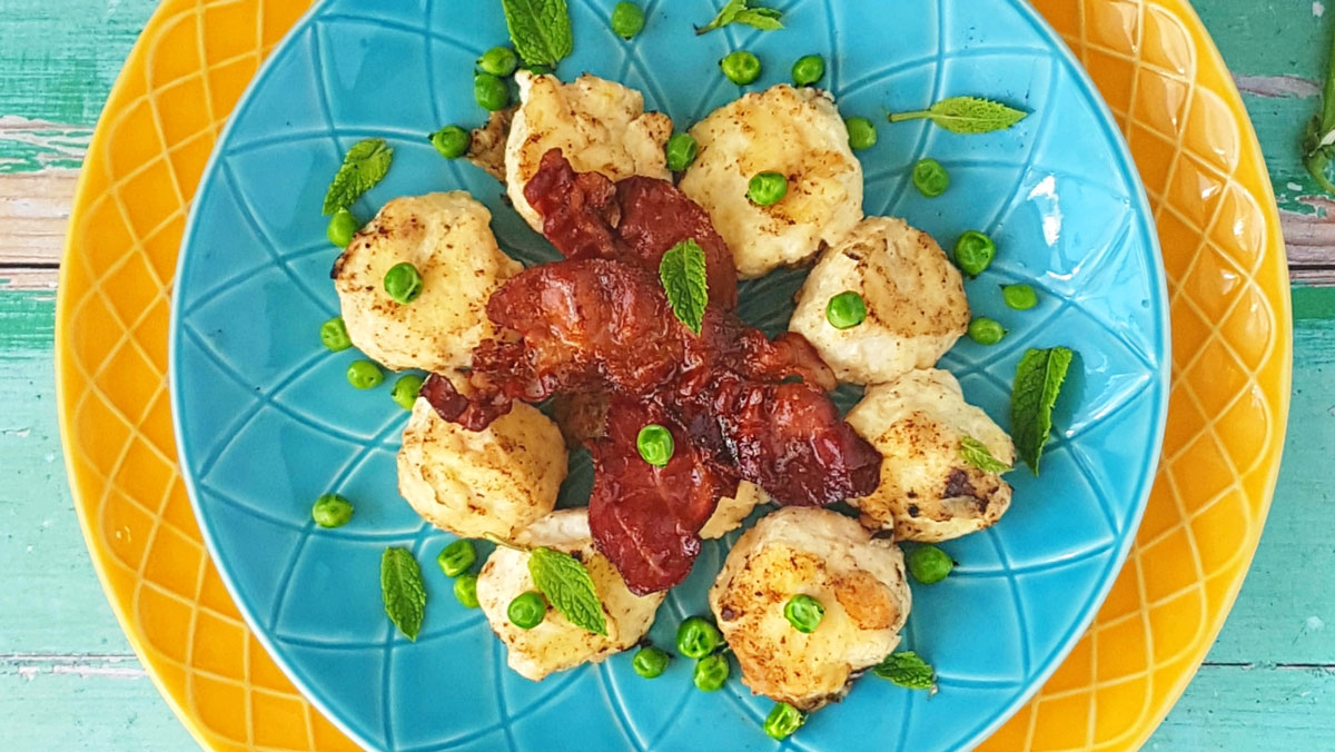 Gnudi with Fresh Peas served on a blue plate and topped with pancetta