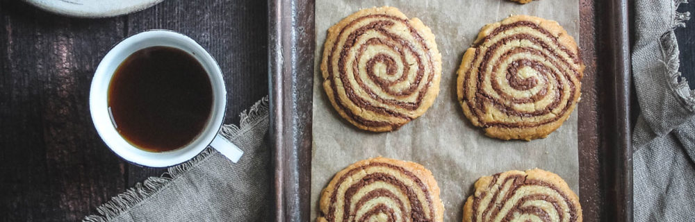 Pinwheel Shortbreads served on parchment paper and on a baking tray next to a cup of tea