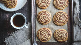 Pinwheel Shortbreads served on parchment paper and on a baking tray next to a cup of tea