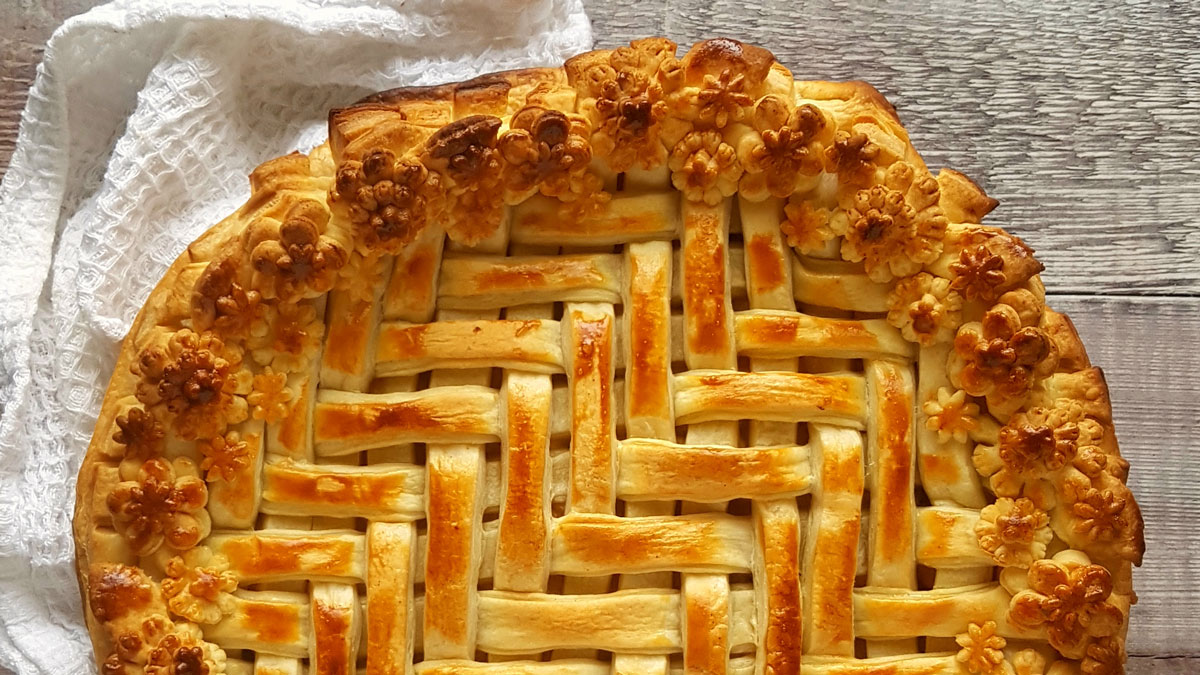 March Pie decorated with pastry flowers around the edge on a wooden table