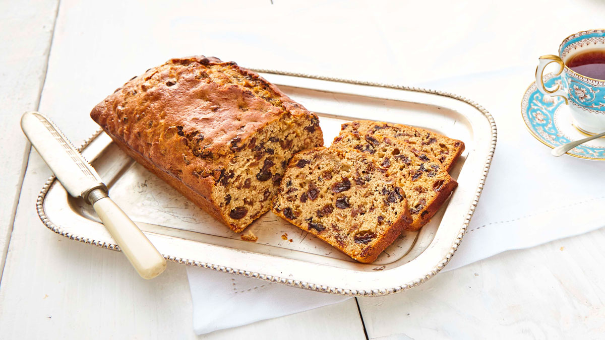 Yorkshire Gin Tea Loaf served on a silver tray, sliced and with a cup of tea in the background