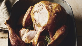 The Perfect Roast Turkey with Chestnut Stuffing served in a baking dish, with some of the turkey carved