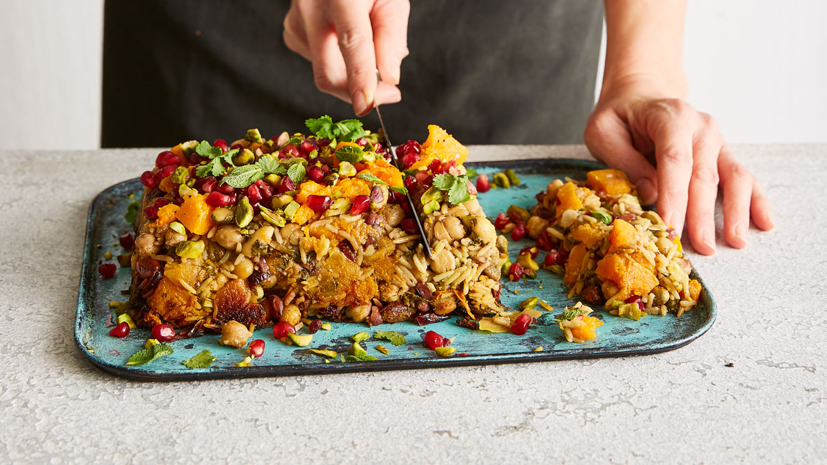 Butternut Squash , Aubergine and Chickpea Loaf being sliced and served on a roasting tray