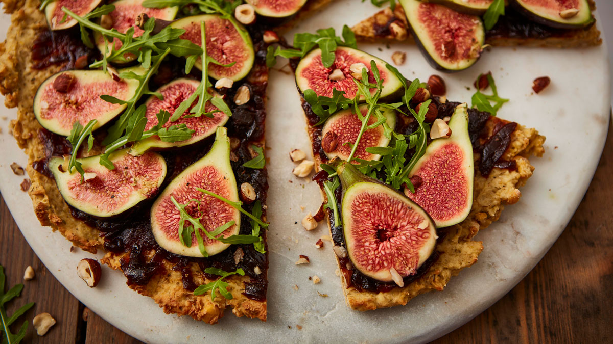 Vegan Chickpea Pizza sliced up and served on a white marble board