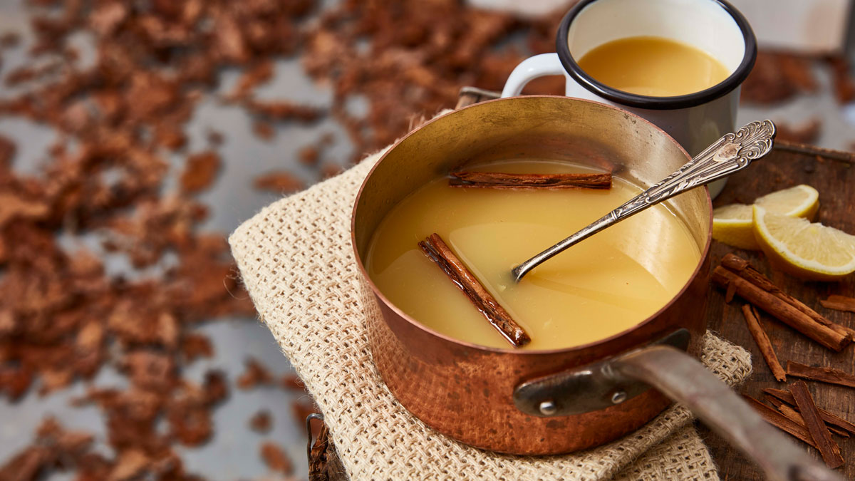 Warmed Mulled Apple and Gin served on a copper pan with cinnamon sticks